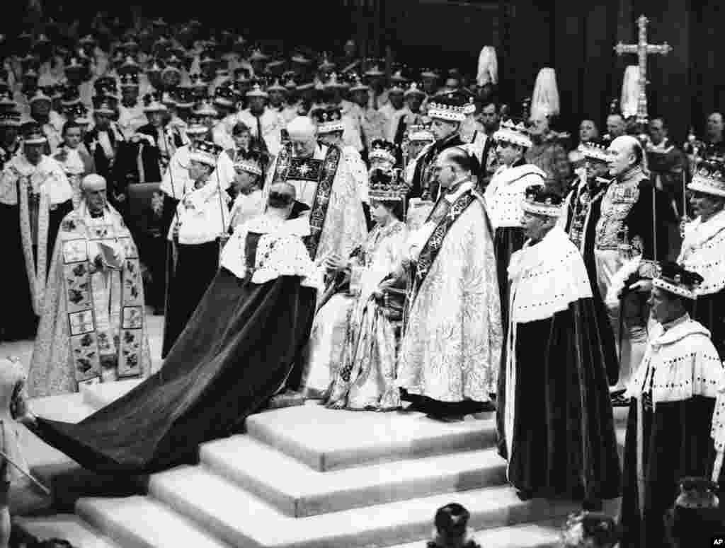 Dikelilingi oleh para Pastor dan dayang-dayangnya, Ratu Elizabeth II duduk di "Chair of Estate" di Westminster Abbey, London, 2 Juni 1953, sebelum upacara naik tahta sebagai Ratu Inggris. 