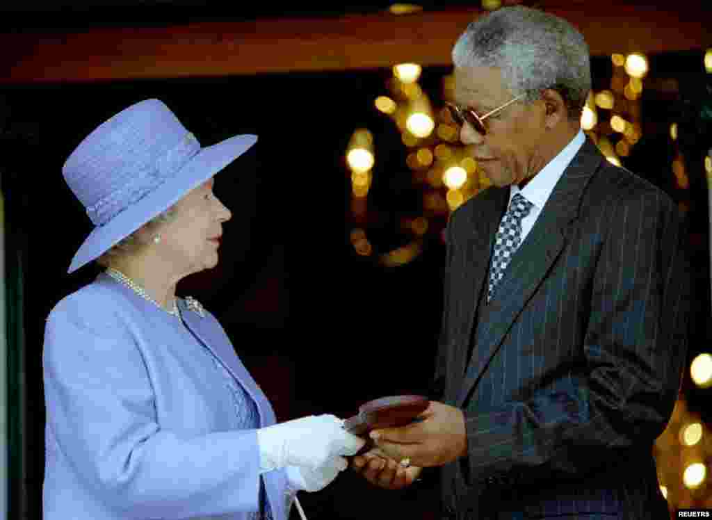 Britain's Queen Elizabeth II presents the Order of Merit medal to President Nelson Mandela at the start of a brief meeting at Mandela's office, March 20, 1995. The Queen is in South Africa, her first to the country since 1947