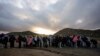 FILE - Asylum-seeking migrants line up in a makeshift, mountainous campsite to be processed after crossing the border with Mexico, Feb. 2, 2024, near Jacumba Hot Springs, California.