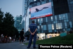 Seorang pria menonton siaran berita CCTV yang menunjukkan jet tempur di dekat Taiwan oleh Komando Teater Timur Tentara Pembebasan Rakyat China (PLA), di sebuah pusat perbelanjaan di Beijing, China, 3 Agustus 2022. (Foto: REUTERS/Thomas Petrus)