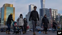 资料照片：行人穿过北京中心商务区办公楼附近的交通路口。（2024年2月8日）