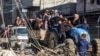 Orang-orang mengendarai gerobak yang ditarik traktor melewati puing-puing bangunan yang hancur dan menara masjid di Rafah, Jalur Gaza selatan, 14 Februari 2024. (MOHAMMED ABED / AFP)