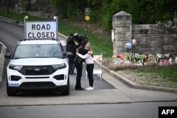 Seorang perempuan memeluk seorang polisi di pintu masuk kampus Kovenan di Gereja Presbiterian Kovenan, Nashville, Tennessee, 28 Maret 2023. (Foto: Brendan SMIALOWSKI/AFP)