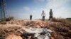 Palestinian men walk towards a crater and debris caused by an improvised explosive device which targeted an Israeli military jeep, in the northern Palestinian city of Jenin, in the Israeli occupied West Bank on June 27, 2024.