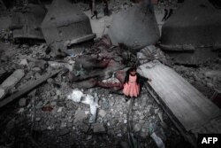 Seorang gadis Palestina mengenakan gaun merah muda berdiri di tengah reruntuhan Masjid Al-Faruq yang hancur akibat pengeboman Israel, di Rafah di Jalur Gaza selatan. (Foto: AFP)