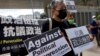 FILE - Pro-democracy activist Lee Cheuk-yan, center, holds placards as he arrives at a court in Hong Kong, April 1, 2021. Hong Kong national security police arrested, March 9, 2023, Lee's wife Elizabeth Tang, herself a labor activist, after visiting her husband in prison.