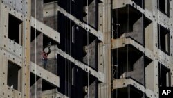 FILE - A worker uses a drill during construction of new apartment buildings in Beijing, China, Oct. 26, 2021.