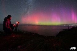 Fotograf snima Auroru Australis, takođe poznatu kao polarna (južna) svetlost, dok sija na horizontu iznad voda jezera Elsmere na periferiji Krajstčerča, Novi Zeland, 24. aprila 2023.