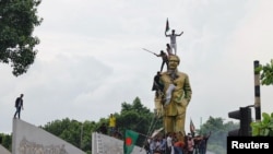 ဘင်္ဂလားဒေ့ရှ်ဝန်ကြီးချုပ် နုတ်ထွက်ရေးတောင်းဆိုသူတွေက ဒက္ကာမြို့မှာရှိတဲ့ နိုင်ငံ့ဖခင်ကြီး Sheikh Mujibur Rahman ရဲ့ရုပ်တုပေါ်တက်ပြီး ဖျက်စီးနေကြပုံ။ (သြဂုတ် ၅၊ ၂၀၂၄) 