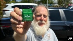 Evan Burroughs, who touts the virtues of an Oregon pilot program that charges motorists by the distance their vehicle travels rather than the gas it uses, displays a tracking device the program uses, in Salem, Ore., June 21, 2023. 