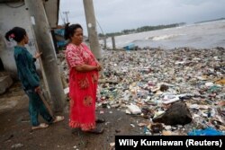Solikah, 58, dan Cartini, 35, mengamati sampah, sebagian besar plastik dan sampah rumah tangga, yang menutupi pantai di lingkungan mereka di desa nelayan Teluk, Pandeglang, Banten, Maret 15, 2024. (Foto: REUTERS/Willy Kurniawan)