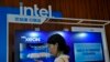 FILE - A woman checks her smartphone near an Intel booth promoting Xeon chips during a tech summit in Beijing, Aug. 16, 2023. 