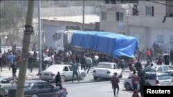 Orang-orang mengejar di belakang konvoi truk bantuan yang melaju ke Gaza dari penyeberangan Rafah, 9 April 2024, dalam tangkapan layar yang diambil dari video. (REUTERS TV/via REUTERS)