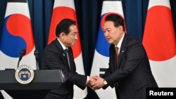 Presiden Korea Selatan Yoon Suk Yeol berjabat tangan dengan Perdana Menteri Jepang Fumio Kishida selama konferensi pers bersama setelah pertemuan mereka di kantor kepresidenan di Seoul pada 7 Mei 2023. (Foto: Jung Yeon-je via REUTERS)