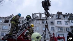 Rescue workers climb by ladder as they clear the rubble of the residential building which was destroyed by a Russian rocket in Pokrovsk, Ukraine, Feb. 15, 2023. 