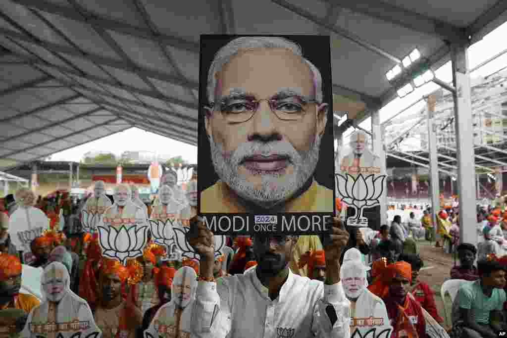 Pendukung Partai Bharatiya Janata (BJP) membawa foto Perdana Menteri Narendra Modi saat mereka menghadiri rapat umum yang disampaikan oleh Modi di Hyderabad, India.