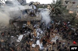 Warga Palestina berkumpul di sekitar rumah keluarga Shehada yang hancur menyusul pemboman Israel terhadap Rafah di Jalur Gaza selatan pada 14 Desember 2023. (Foto: AFP)
