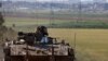 An Israeli soldier gestures, as he rides in an armored personnel carrier (APC), near the Israel-Gaza border, in Israel, March 10, 2024. 