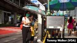 People carry umbrellas and hand-made fans to cool down from the extreme heat in Bangkok, Thailand, April 23, 2023.