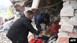Dua orang mencari di antara puing-puing sebuah rumah setelah serangan rudal Rusia di desa Velyka Vilshanytsia, Ukraina, sekitar 50 km dari kota Lviv, hari 9 Maret 2023.