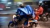 Pengendara motor mengenakan jas hujan saat berkendara saat hujan deras mengguyur Ibu Kota Jakarta pada 19 Januari 2022. (Foto: BAY ISMOYO/AFP)