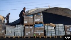 Seorang pria menurunkan bantuan kemanusiaan dalam konvoi truk memasuki Jalur Gaza dari Mesir melalui perbatasan Rafah, 21 Oktober 2023.