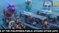 FILE - Kapal penjaga pantai China (kiri) mendekati kapal Filipina (tengah) saat terjadi insiden di Second Thomas Shoal di perairan Laut Cina Selatan, 17 Juni 2024. (Handout / ANGKATAN BERSENJATA KANTOR PUBLIK FILIPINA / AFP) 