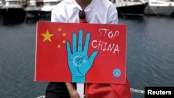 Seorang pria etnis Uighur memegang plakat ikut serta dalam protes terhadap China untuk menandai peringatan 14 tahun kerusuhan Urumqi di Istanbul, Turki, 5 Juli 2023. (Foto: Reuters)