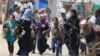 Palestinians rush during Israeli bombardment in an area of Rafah, June 19, 2024. The U.N. High Commissioner for Human Rights said it appeared Israel made no attempt to 'effectively distinguish' between Palestinian civilians and Hamas fighters in its bombing campaign of Gaza.