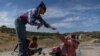 An aid worker provides food to a six-year-old migrant from Guatemala and her seven-year-old brother after they crossed into the United States from Mexico with their family in Jacumba Hot Springs, California, May 20, 2024.