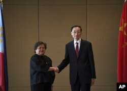 Theresa Lazaro, kiri, Wakil Menteri Luar Negeri Filipina untuk Hubungan Bilateral dan Urusan Asia Departemen Luar Negeri, berjabat tangan dengan Sun Weidong, Wakil Menteri Luar Negeri China, sebelum dimulainya pertemuan di Manila, Kamis, 23 Maret 2023. (Foto: via AP)