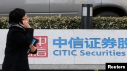FILE - A woman walks past a signage for Citic Securities at its head office in Beijing, China, March 27, 2013. Xu Zuo, vice president at China Citic Group, is "suspected of serious disciplinary and legal violations," an inspection commission said Sunday.