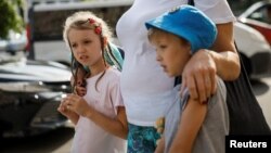 10-річна Ангеліна та 9-річний Олександр возз'єднані зі своєю матір'ю Світланою після повернення з окупованої території України, 6 вересня 2023. За даними Києва, до Росії було депортовано понад 19 500 дітей. Повернути вдалось лише близько 400 дітей. REUTERS/Gleb Garanich