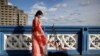 FILE - A Chinese student who calls herself Evie makes a video for her followers on Douyin, a Chinese social media network, on Tower Bridge in London, March 25 2023. In late May 2024, Douyin announced a new verification mechanism for suspected fake content.