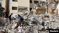 Anak-anak Palestina berjalan di tengah puing-puing bangunan yang rusak akibat serangan Israel di kamp Jenin di Tepi Barat yang diduduki Israel, 23 Mei 2024. (REUTERS /Raneen Sawafta)