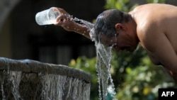 Seorang pria menyiramkan air untuk mengatasi suhu ekstrem gelombang panas di Guadalajara, negara bagian Jalisco, Meksiko, 12 Juni 2023. (Foto: Ulises Ruiz/AFP)