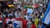 Penggemar sepak bola mengibarkan bendera negara peserta saat parade jelang kick-off Piala Dunia FIFA Qatar, di Desa Pambusuang, Sulawesi Barat, Minggu, 20 November 2022. (Foto: AP)