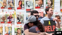 Sejumlah warga berkumpul menggelar protes di depan poster dari para sandera yang ditawan Hamas, yang terpasang di sebuah lokasi di Tel Aviv, pada 25 April 2024. (Foto: AFP/Jack Guez)