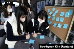 Para fans menuliskan pesan-pesan penyemangat untuk Jo Yoong-jae dan Choi Seo-eun dalam acara jumpa fans di Seoul, Korea Selatan, 11 Februari 2023. Keduanya adalah peserta acara reality show kencan "Single's Inferno 2." (Foto: Soo-hyeon Kim/Reuters)
