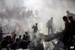 Palestinians inspect the rubble of destroyed buildings following Israeli airstrikes on the town of Khan Younis, southern Gaza Strip, Oct. 26, 2023.