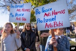 Noa Friedan, 13, left, and Eila Friedan, 11, of Philadelphia, hoist signs saying "Pro Israel, Anti Hamas, Pro Peace, Anti Bibi" while rallying on the National Mall in Washington to support Israel, Nov. 14, 2023.