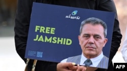 Seorang demonstran membawa poster berisi gambar Jamshid Sharmahd dalam aksi menuntut pembebasan terhadap Sharmahd di luar Kementerian Luar Negeri Jerman di Berlin, pada 31 Juli 2023. (Foto: AFP/Ina Fassbender)