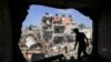 Seorang remaja berdiri depan lubang yang tadinya sebuah dinding pada sebuah bangunan yang dihantam roket Israel, di Khan Yunis, di selatan Jalur Gaza, 8 November 2023. (Foto: Mahmud Hams/ AFP)