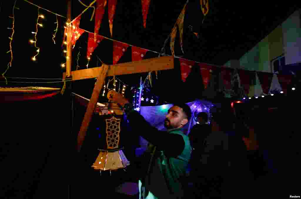 عرب دنیا میں رمضان کی آمد پر خاص طور پر تیار کیے گئے فانوس سے سجاوٹ کی جاتی ہے۔ جنگ زدہ غزہ سے بے گھر ہونے والا ایک فلسطینی رفح میں اپنے خیمے کے باہر فانوس لگا رہا ہے۔ 