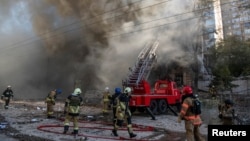 FILE - Firefighters help a local woman evacuate from a residential building destroyed by a Russian drone strike, which local authorities considered to have been made with an Iranian-made Shahed-136, in Kyiv, Ukraine, Oct. 17, 2022.