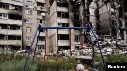 A teddy bear is seen next to a swing, next to buildings destroyed by military strikes, as Russia's invasion of Ukraine continues, in Saltivka, one of the most damaged residential areas of Kharkiv, July 17, 2022. 