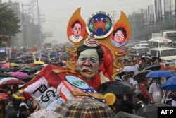 Para pengunjuk rasa yang diguyur hujan, berbaris dengan patung yang menggambarkan Presiden Filipina Ferdinand Marcos Jr dalam aksi demo bertepatan dengan pidato kenegaraan pertama presiden baru, di Quezon City, pinggiran kota Manila, 25 Juli 2022. (Ted ALJIBE / AFP)
