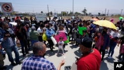FILE - People gather as Rev. Albert Rivera, bottom left, speaks during a protest of people waiting in Mexico as they hope to apply for asylum, May 19, 2022, in Tijuana, Mexico.