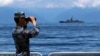 FILE - In this photo provided by China's Xinhua News Agency, a People's Liberation Army member looks through binoculars during military exercises as Taiwan's frigate Lan Yang is seen at the rear, Aug. 5, 2022. (Lin Jian/Xinhua via AP)