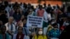 Seorang demonstran menunjukkan poster yang memprotes penundaan hukuman bagi sejumlah pria yang dipidana melakukan pemerkosaan massal terhadap seorang perempuan muslim, di New Delhi, India, Sabtu, 27 Agustus 2022. (Foto: Altaf Qadri/AP Photo)